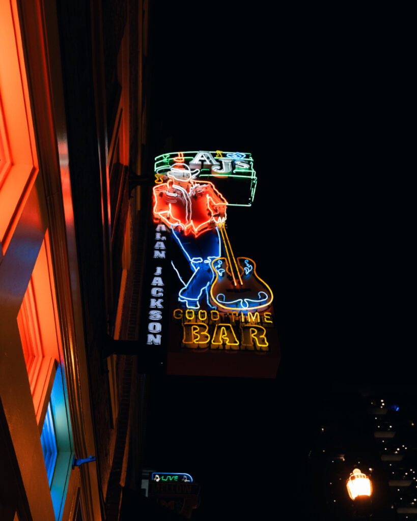 AJ's Good Time Bar exterior in Nashville with neon signs and a bustling crowd, hinting at a vibrant nightlife.