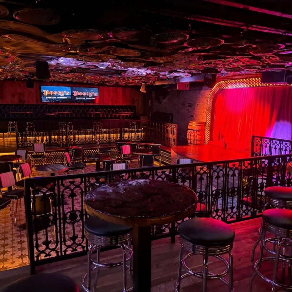 Interior of Posty’s Bar Nashville with stage, neon lights, and stylish seating.