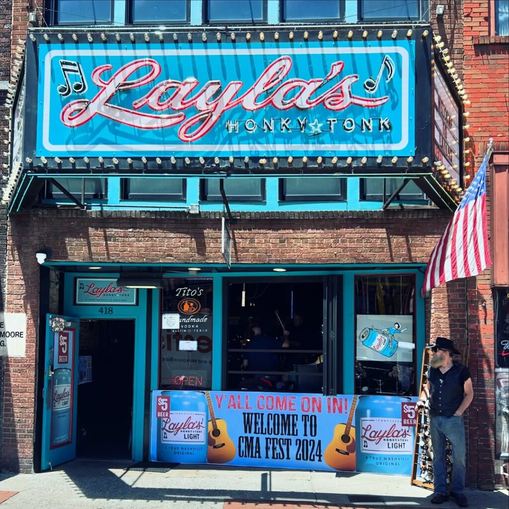 Exterior of Layla’s Honky Tonk in Nashville with bright turquoise trim, neon signage, and a CMA Fest 2024 welcome banner.
