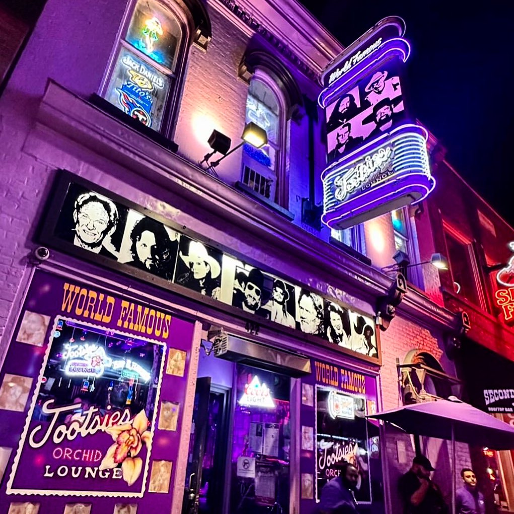 Exterior of Tootsie’s Orchid Lounge on Broadway in Nashville, with its signature purple facade and neon signs glowing at night.