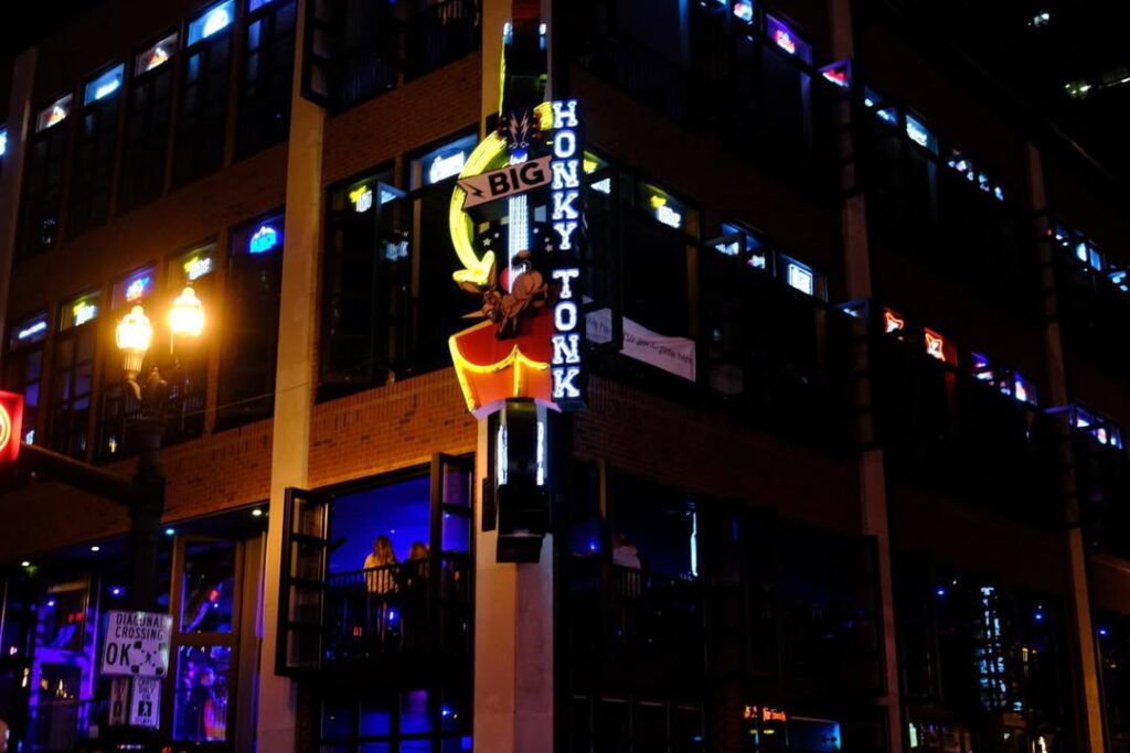 Exterior of Kid Rock’s Big Honky Tonk & Steakhouse on Broadway in Nashville, with neon signs glowing above the entrance.