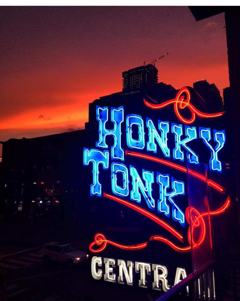 Honky Tonk Central neon sign with blue and red lighting against an orange sunset sky in Nashville