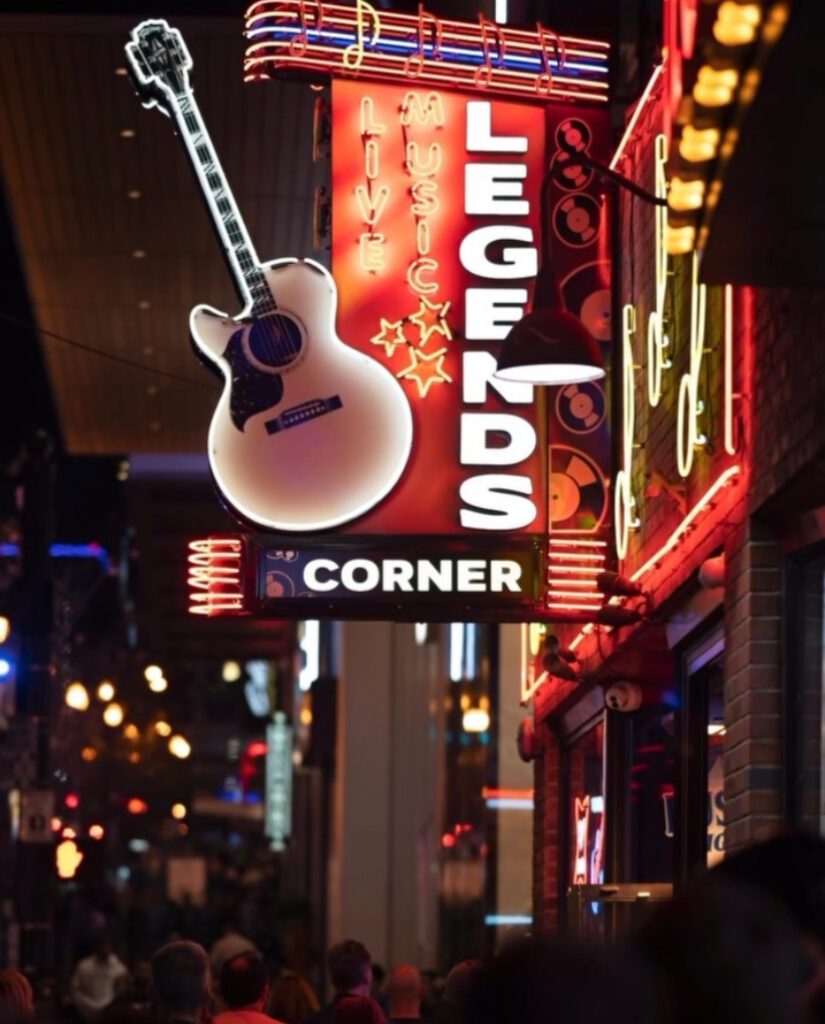 Exterior neon sign of Legends Corner bar in Nashville, featuring a glowing guitar and red marquee promoting live music.