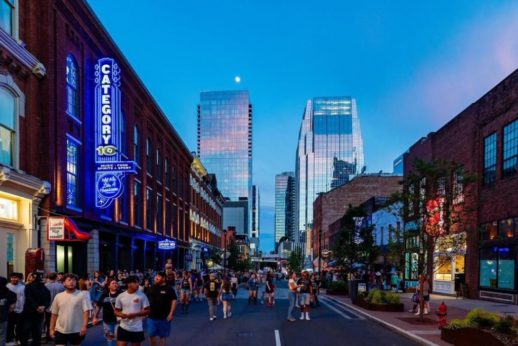 Evening crowd outside Category 10 bar in downtown Nashville with neon signage, historic architecture, and modern skyscrapers