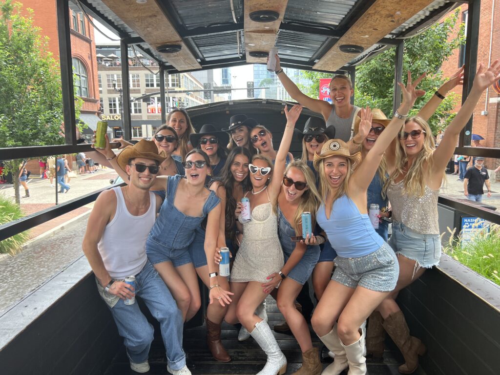 Group with hands up on a Rowdy Bus party bus driving down Broadway in Nashville