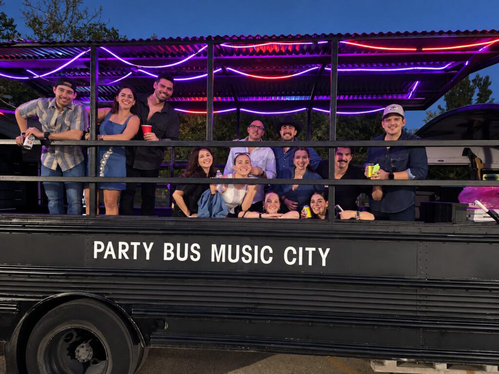 Mixed group on a Rowdy Bus party bus at dusk with LED lights on