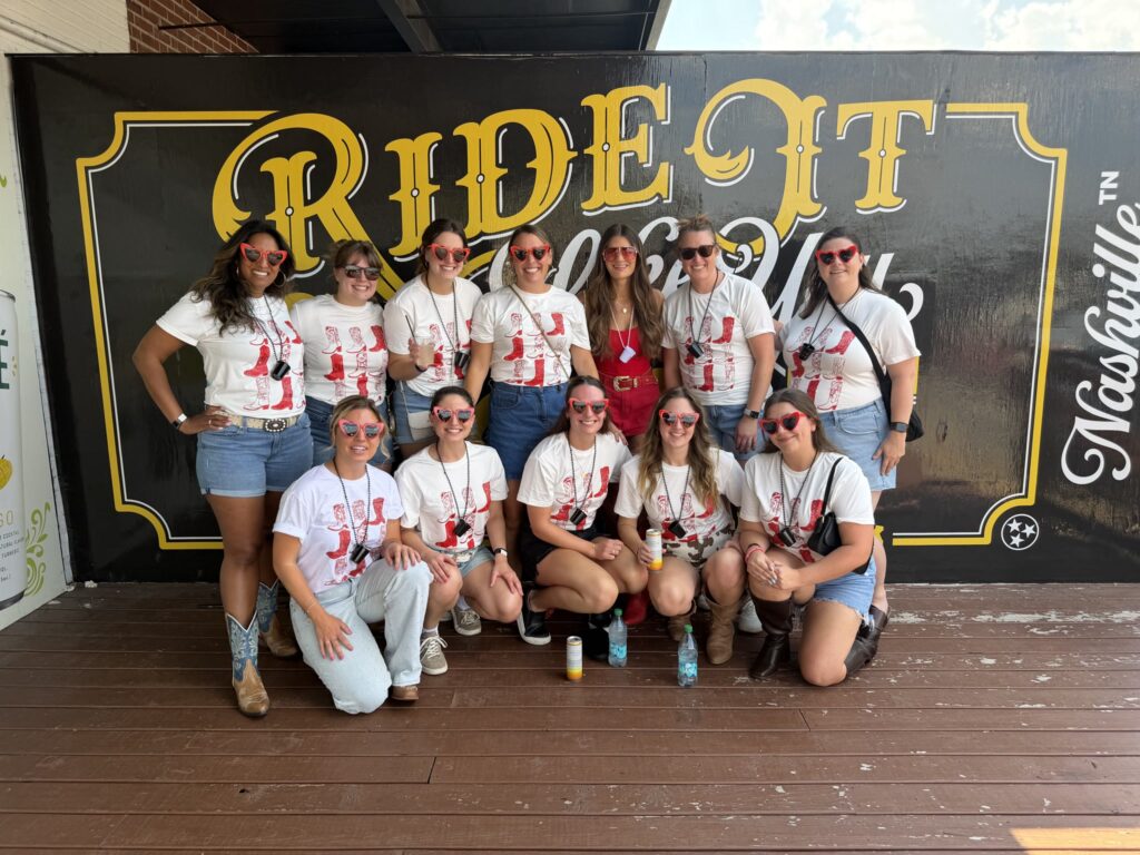 Girls' trip group in matching shirts at the Ride It Nashville wall before their Rowdy Bus tour